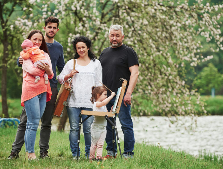 Family have good time in the parkland. Young painter teaching how to draw